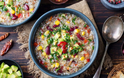 A blue bowl with Mexican Quinoa Soup and a potato-sack like mat with a silver spoon next to it