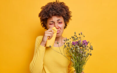 A girl suffering from hay fever with red eyes and a runny nose with a yellow background